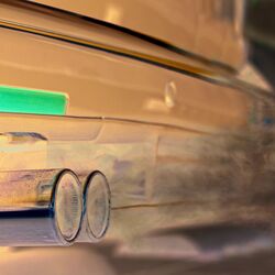 Das Bild zeigt den Auspuff eines Autos, aus dem Abgase herausströmen.