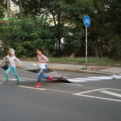 Kinder laufen mit einem Zebrastreifen über die Straße