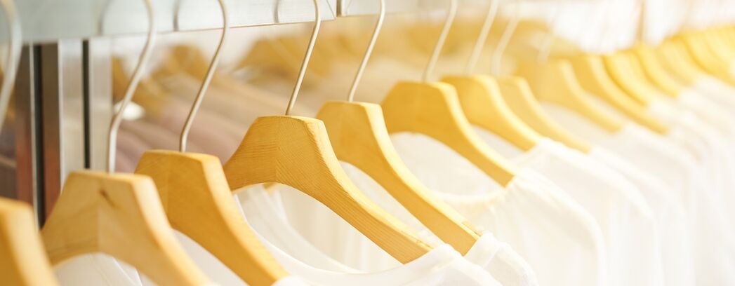 Weiße T-Shirts auf Bügeln aufgehängt in einem Geschäft