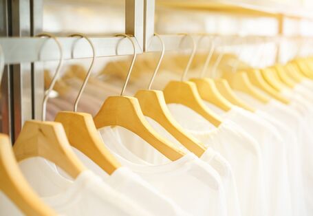 Weiße T-Shirts auf Bügeln aufgehängt in einem Geschäft