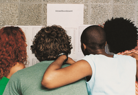 Menschen schauen Zettel an einer Wand an