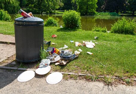 Plastikmüll Picknikartikel quellen aus einer Mülltonne im Park