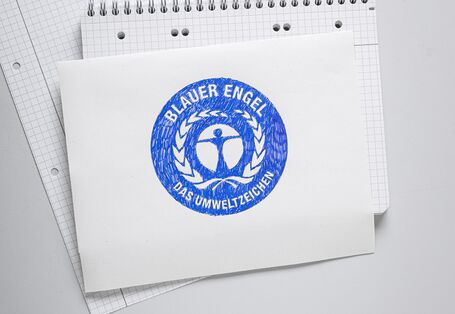 Auf einem Blatt Papier wurde das Umweltzeichen Blauer Engel gemalt.