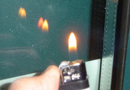 Feuerzeugtest: Jemand hält ein Feuerzeug vor die Verglasung und es spiegelt sich die Flamme an der Glasoberfläche. 