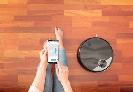 Frau bedient Saugroboter über Handy-App
