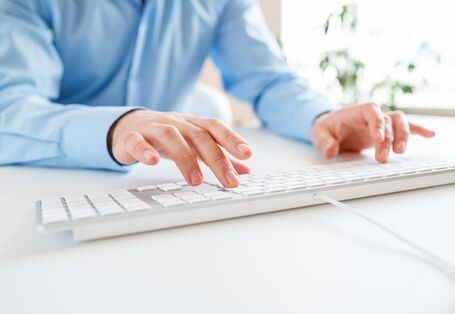 Mann tippt auf einer Computertatstatur.