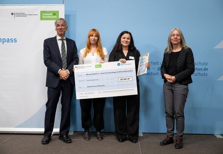 Stefan Tidow und Dr. Bettina Rechenberg überreichen einen Scheck an die Gewinnerinnen des Vereins "BÄR meets ADLER e.V. - Verein für ein gutes Morgen in Berlin und Brandenburg".