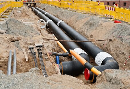 Fernwärmeleitungen in einem Graben, die frisch verlegt werden