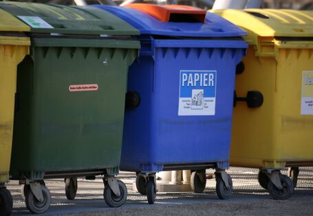 Müllcontainer in grün, blau und gelb für verschiedene Abfälle.