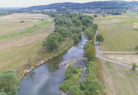 Luftbild der Fulda mit schräg zur Fließrichtung eingebrachten Steinen. Die dadurch abgelenkte Strömung hat bereits eine Erosion des Ufers bewirkt.