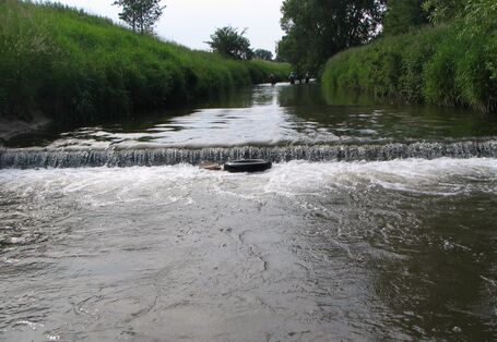 Foto: Eine Sohlschwelle in der Helme bei Nordhausen, an dem das Wasser mehrere Zentimeter hinabstürzt.