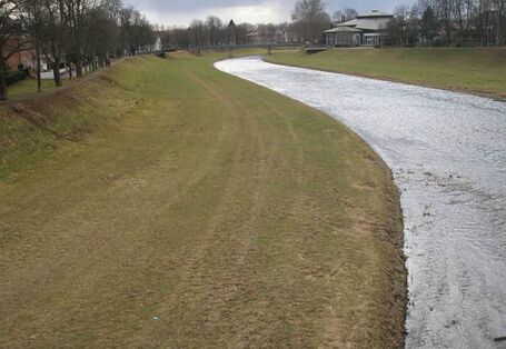 Foto: Ein Abschnitt der Murg vor der Renaturierung. Die Ufer des Flusses sind bis auf kurz gehaltenes Gras völlig frei von Vegetation. Das Gewässer selbst ist sehr monoton, ohne Inseln, Kiesbänke oder andere Strukturen.