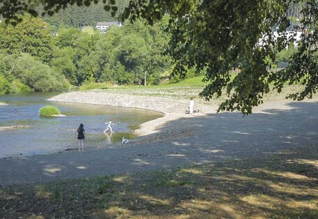 Foto: Erholungssuchende Menschen an der renaturierten Ruhr in Oeventrop. Im Gewässer befinden sich kleine Kiesbänke. Im Hintergrund wächst üppige Vegetation entlang der Ufer.