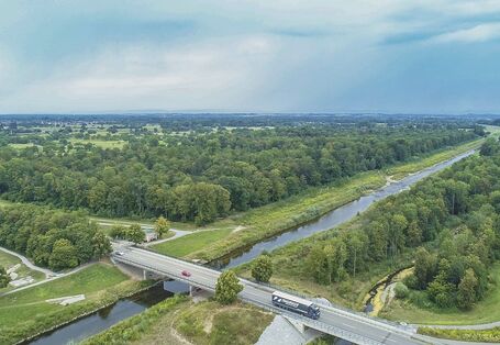 Luftbild des Flusses Murg bei Rastatt. Entlang des geradlinigen Hauptgerinnes liegt ein strukturreiches Nebengerinne, das als Überflütungsfläche für Hochwasser dient. Im Hintergrund liegen ausgedehnte Auwaldflächen. Am Bildrand stehen Gebäude der Stadt.