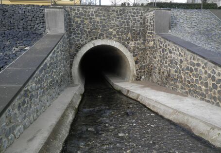 Entrance of a stream into a pipe. The banks and the riverbed are concreted.
