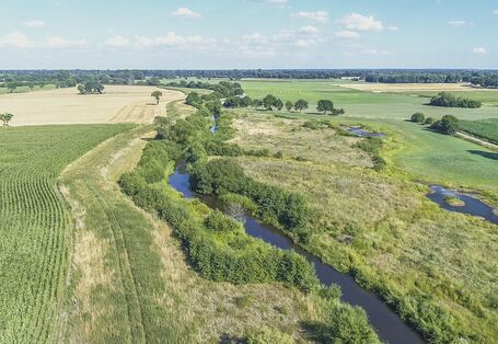 Luftbild der Wümme mit durchgehendem Gehölzsaum, umgeben von landwirtschaftlich genutzten Grün- und Ackerlandflächen.