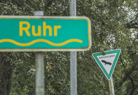Foto: Ein Schild mit der Aufschrift „Ruhr“. Im Hintergrund ein Schild mit der Aufschrift „Naturschutzgebiet“.