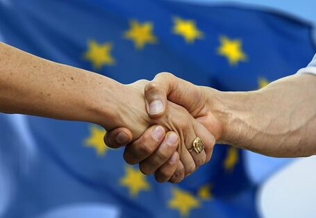 schüttelnde Hände vor der Europaflagge