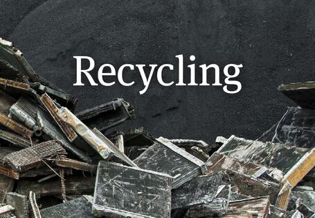 Das Wort Recycling vor schwarzem Hintergrund, darauf auch ausrangierte Kühlaggregate.