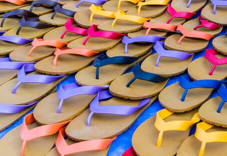 Abgebildet sind mehrere gestapelte Paar Flipflops in verschiedenen Farben.