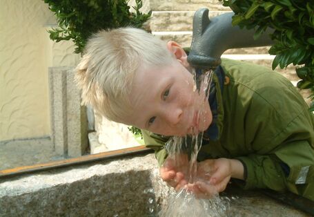 A boy drinking at the tap