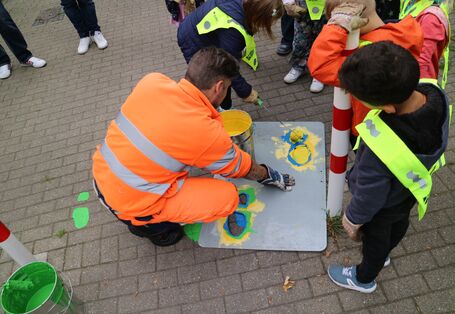 Schülerinnen und Schüler malen Füße unter Anleitung in den Straßenraum