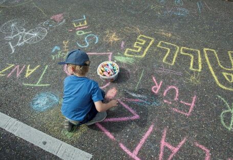 Kind malt auf der Straße mit Straßenkreide
