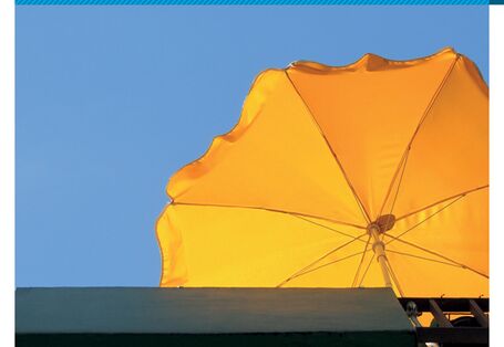 Cover von "Anpassung an den Klimawandel: Hitze in der Stadt" mit einem Foto eines gelben Sonnenschirms, der auf einem Balkon steht