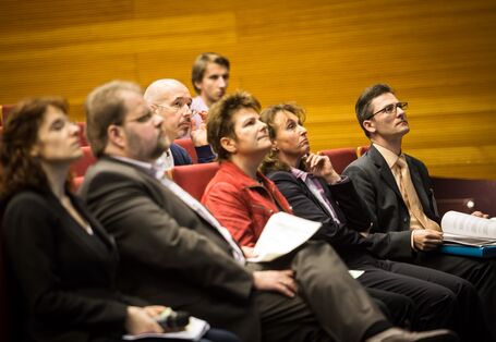 Die Workshopteilnehmer sitzen in Stuhlreihen und hören gebannt den Ausführungen der Vortragenden zu.