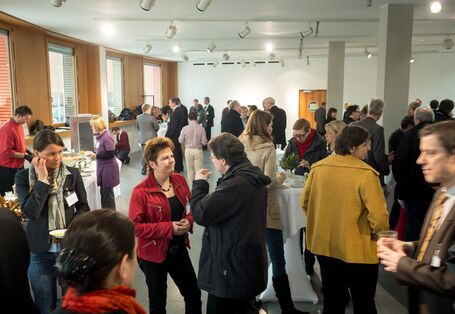 Veranstaltungsteilnehmer die in der Mittagspause in Gruppen zusammenstehen und sich unterhalten und essen und trinken.