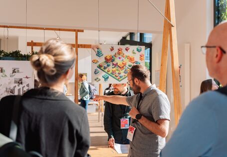 Teilnehmende betrachten graphische Arbeiten in der Ausstellung „Stadtansichten“.