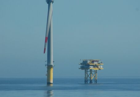 Das Foto zeigt eine Windenergieanlage des Offshore-Windparks Alpha Ventus und daneben das Umspannwerk des Parks.