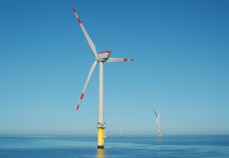 Das Foto zeigt drei Strukturen des Offshore-Windpark Alpha Ventus. Im Vordergrund sieht man eine Windenergieanlage mit Monopile-Fundament. Im Hintergrund sieht man eine Anlage mit Jacket-Fundament (als Fachwerk konstruierte Gründungsstrukturen) und die Forschungsstation FINO1