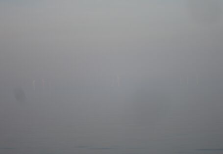 Das Foto zeigt den Blick auf den Offshore-Windpark Alpha Ventus. Die 12 Windenergieanlagen sind durch den Nebel kaum erkennbar.