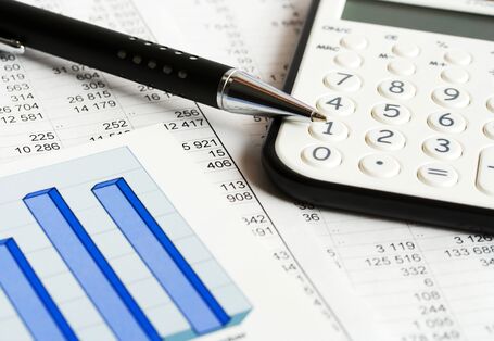 Das Bild zeigt einen Stift und einen Taschenrechner, die auf einem Ausdruck mit Tabellen und Diagramm liegen.