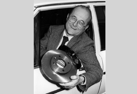 Von Lersner lehnt sich aus einem Autofenster und hält asbestfreie Bremsbeläge in die Kamera