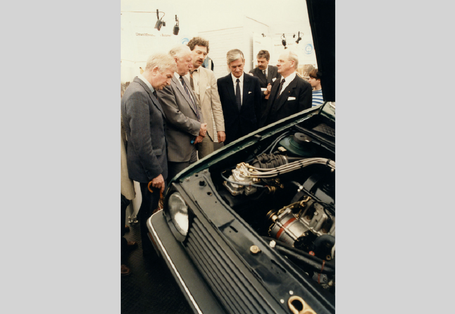 Ein Mitarbeiter des UBA informiert an einem Stand des UBA vor einer geöffneten Pkw-Motorhaube