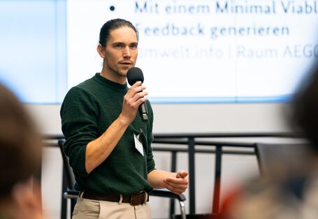 junger Mann hält Vortrag mit Mikrofon