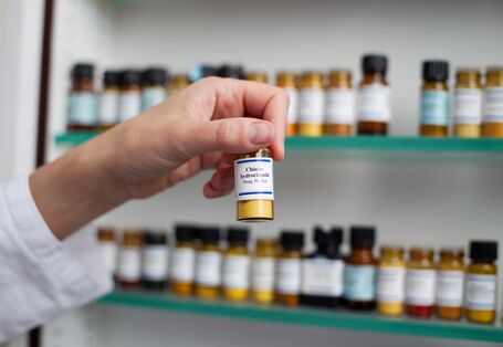 ein Apotheken-Mitarbeiter nimmt ein beschriftetes Fläschchen aus dem Regal