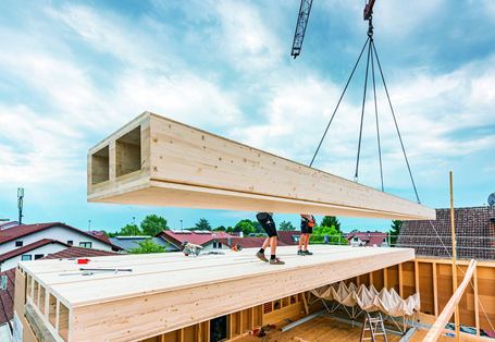 Vorgefertigte Holzelemente werden mit einem Kran als Geschossdecke auf einen Holzbau gesetzt