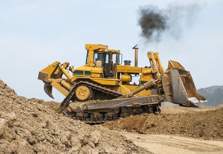 ein Bulldozer stößt eine schwarze Abgaswolke aus