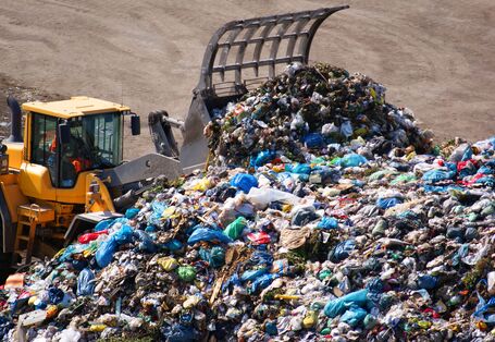 Radlader türmt Abfälle auf einer Deponie zu einem Berg auf