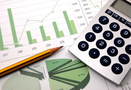 auf einem Tisch liegen ein Blatt Papier mit in grün und weiß gehaltenen Diagrammen, ein Taschenrechner und ein Bleistift