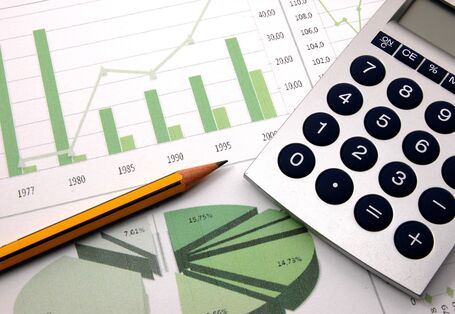 Taschenrechner, Bleistift und Zettel mit grünen Säulen- und Tortendiagrammen