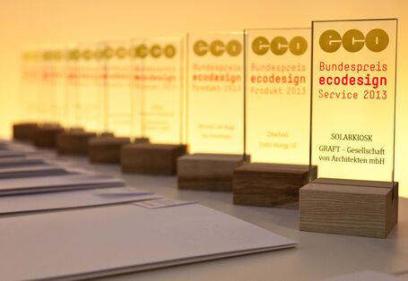 Trophies with the logo of the Bundespreis Ecodesign an the names of the winners standing on a table