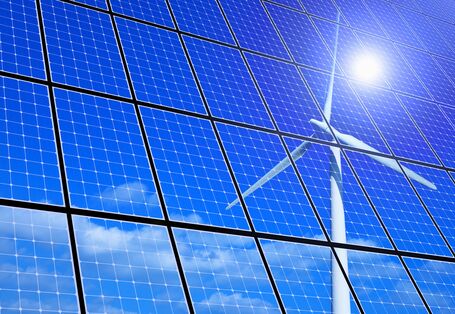 Die Sonne und ein Windrad spiegeln sich in einer Fläche von Solarzellen 