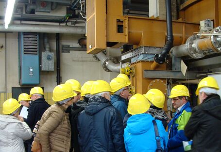 Group of people with yellow hard hats looking at technical installation