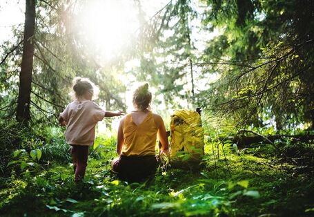 Frau mit Kind sitzend im Wald.