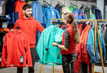 ein junges Pärchen sucht in einem Geschäft zusammen eine wetterfeste Jacke aus