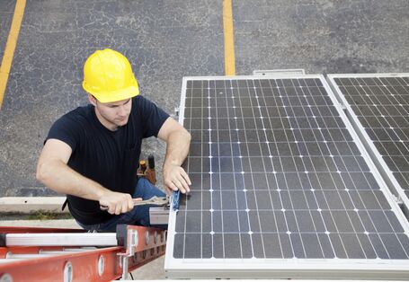 Arbeiter mit gelbem Schutzhelm arbeitet an einer Solaranlage